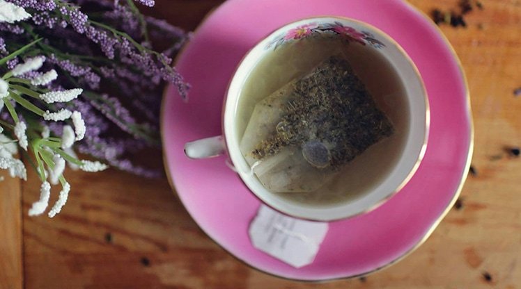 Tasse Tee neben der ein Strauß Lavendel liegt